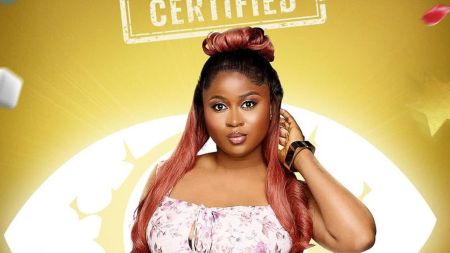 BBNaija Season 10 housemate Imisi poses confidently in her official portrait, wearing a floral dress against a bright yellow background with the word “Certified” displayed above her.