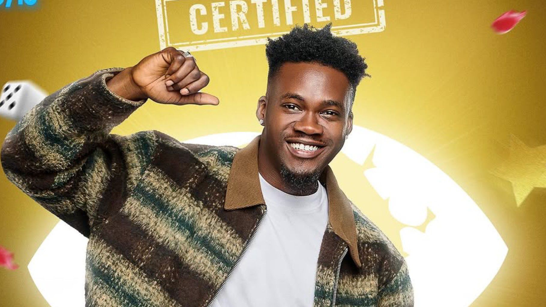 BBNaija housemate Jason poses against the golden certified background, smiling brightly and pointing at himself while wearing a striped jacket over a white shirt.
