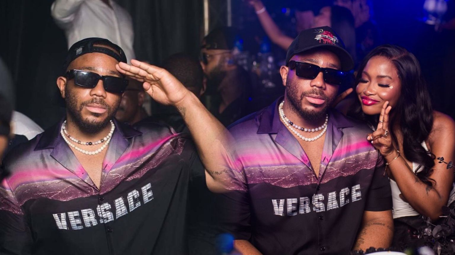 BBNaija stars Kiddwaya and Ilebaye pictured together at a Lagos nightclub, with Kiddwaya wearing a black-and-purple Versace shirt and dark sunglasses, while Ilebaye poses beside him flashing a peace sign.