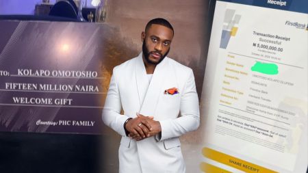 BBNaija star Kola Omotoso stands between a giant cheque showing ₦15 million from PHC Family and a mobile bank receipt confirming ₦5 million transfer as part of his welcome home gifts.