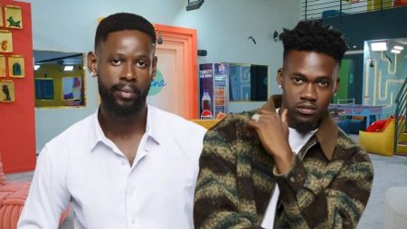 BBNaija Season 10 housemates Mensan and Jason Jae pose inside the Big Brother Naija house, both dressed stylishly and looking composed.