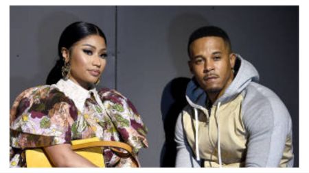 Nicki Minaj and her husband Kenneth Petty pose together, with Nicki wearing a floral puff-sleeve outfit and gold accessories while Kenneth wears a grey and beige hoodie.