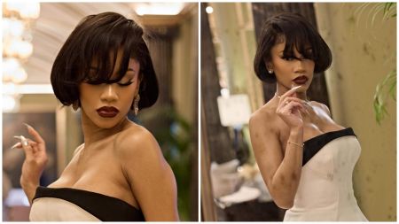 Saweetie poses elegantly indoors wearing a strapless white gown with a black trim, styled in a short vintage bob haircut and deep red lipstick, exuding old-Hollywood glamour.