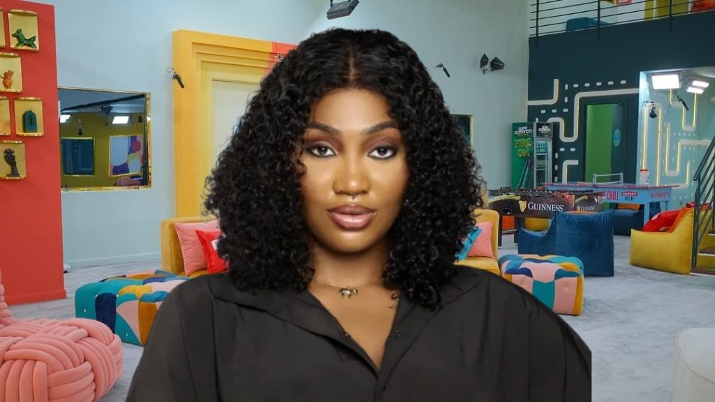 BBNaija Season 10 housemate Sultana poses inside the Big Brother Naija house lounge, wearing a black outfit and curly hair while looking confidently at the camera.