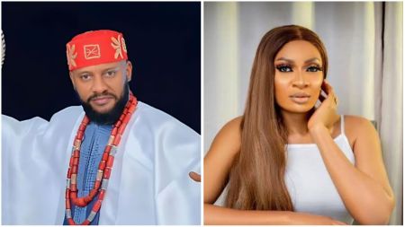 Nigerian actor Yul Edochie is dressed in traditional Igbo attire with red coral beads and a red cap, while May Edochie appears in a white sleeveless outfit with straight brown hair, posing elegantly indoors.