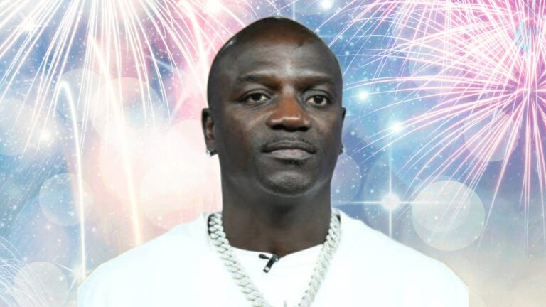 Akon stands against a bright, colourful background filled with fireworks and glowing light effects while wearing a white shirt and a silver chain.