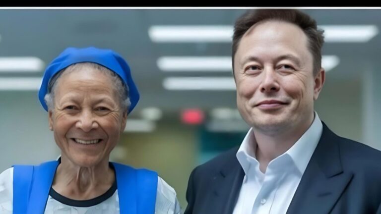 Elon Musk standing beside an elderly woman wearing a blue headscarf and vest, both smiling in a brightly lit indoor setting.
