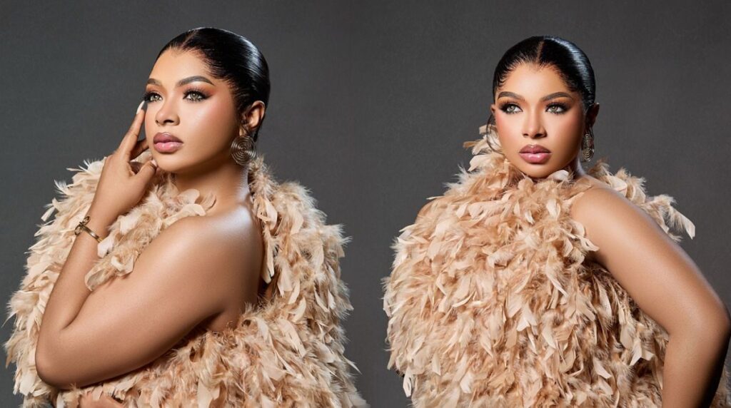 Side-by-side studio portraits of Liquorose wearing a feathered beige outfit, styled with sleek pulled-back hair, bold eye makeup and nude-pink lipstick, posing confidently against a dark grey background.