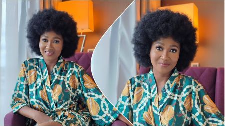 Nollywood actress Mary Njoku sits on a purple chair, wearing a patterned green robe with yellow designs, smiling with a full afro hairstyle in a well-lit indoor setting.