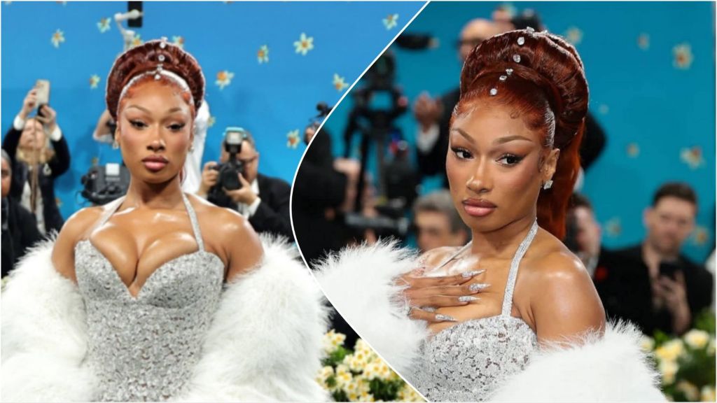 Megan Thee Stallion poses on a red carpet wearing a sparkling silver gown with a white fur shawl, styled with an elegant updo adorned with jewels, while photographers capture her in the background.