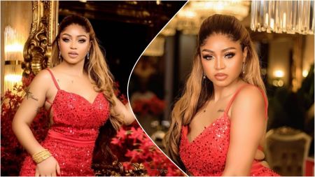 Regina Daniels poses indoors in a red sequinned dress, looking directly at the camera with soft lighting and floral décor in the background.