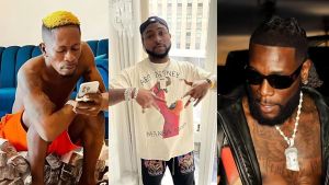A side-by-side collage showing three musicians: Shatta Wale sitting shirtless and looking at his phone, Davido standing indoors wearing a cap and jewellery while posing with his hands, and Burna Boy dressed in black with sunglasses and a chain.