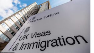 A tall UK government building with a large sign reading “Home Office – UK Visas & Immigration,” photographed from a low angle against a blue sky.