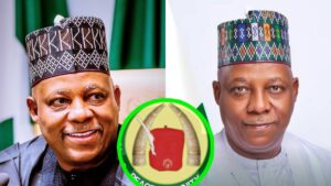 A side-by-side collage showing Nigeria’s Vice President Kashim Shettima. On the left, he is smiling while wearing a black traditional cap and dark outfit with the Nigerian flag blurred behind him. On the right, he appears in a lighter outfit with a multi-coloured traditional cap, facing the camera with a calm expression. At the centre bottom of the collage is a circular emblem featuring two elephant tusks and a red cap.