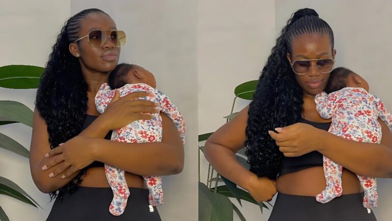 “Real Warri Pikin holds her newborn close while posing in fitted black wear and sunglasses; the baby rests on her chest in a floral onesie as she stands beside indoor plants.”
