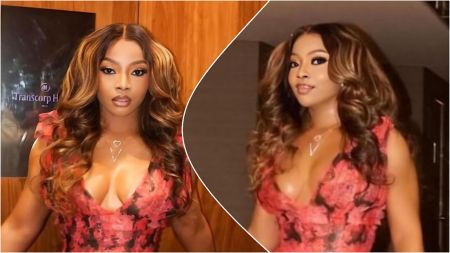 Split-image collage of Nigerian media personality Toke Makinwa wearing a red and black floral-patterned dress with ruffled shoulders and deep V-neckline, paired with a heart-shaped "V" pendant necklace—left: full-body pose indoors in front of wooden paneling and a "Transcorp Hilton" sign; right (circular inset): close-up portrait with loose wavy hair against a darker background.