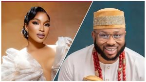 A split image featuring Nigerian actress Tonto Dikeh and her ex-husband, businessman Olakunle Churchill. On the left, Tonto Dikeh is looking over her shoulder, wearing a glamorous, one-shoulder white gown with ruffles, a vintage-style hairstyle, and elegant makeup. On the right, Olakunle Churchill is smiling brightly, wearing a white traditional Nigerian attire (Buba and Sokoto) with a gold traditional cap and large red coral beads around his neck.
