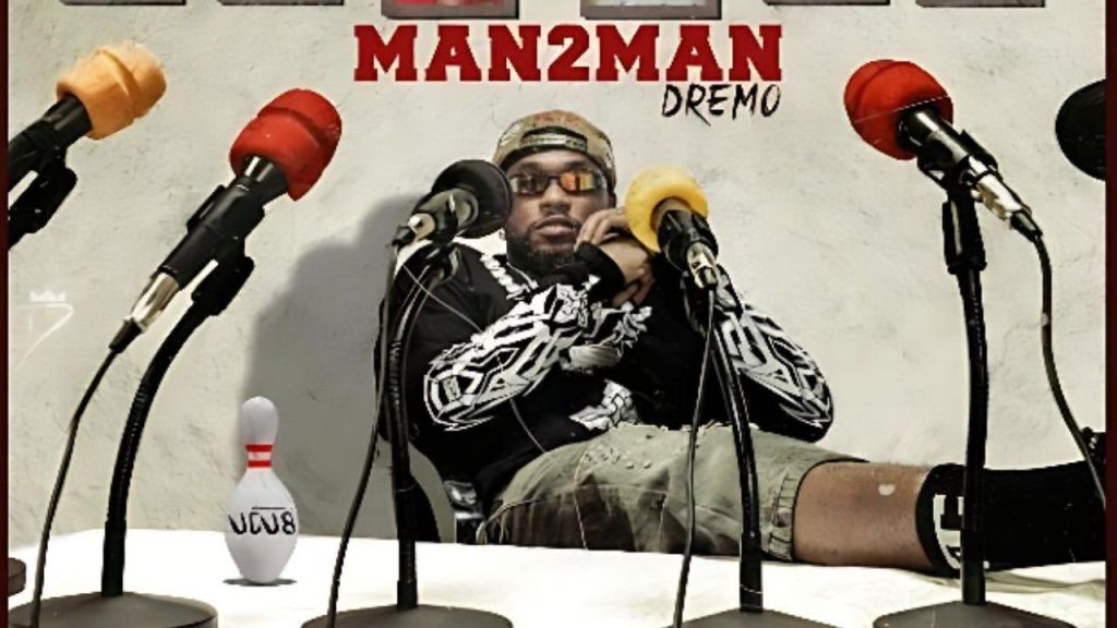 Dremo sitting at a table surrounded by microphones for the Man2Man single cover art.