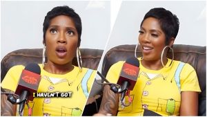 A split image showing Nigerian singer Tiwa Savage during an interview on the Lip Service podcast. On the left, she wears a surprised expression with her mouth slightly open, while on the right, she is smiling and looking away. She is wearing a yellow graphic t-shirt with a trompe-l'œil print, large silver hoop earrings, and has a short, cropped hairstyle. A microphone with the red "Lip Service" logo is visible in the foreground.