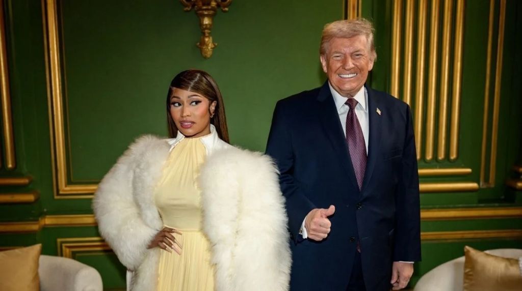 Nicki Minaj, wearing a yellow dress and large white fur coat, stands next to Donald Trump, who gives a thumbs up in a room with green and gold walls.